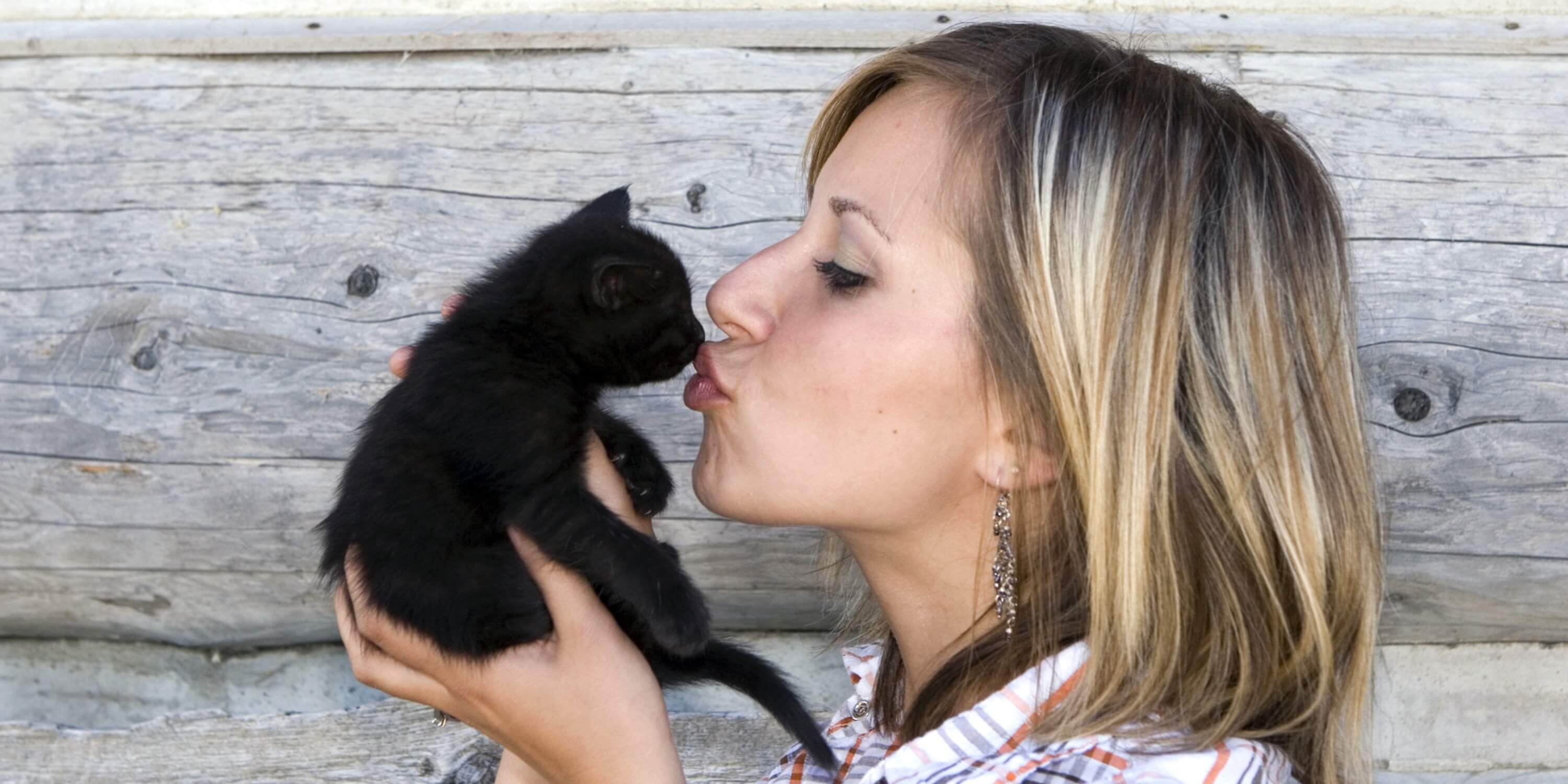 woman kissing black cat
